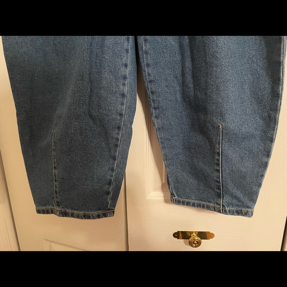 Blue denim jeans that have a flowy design and are somewhat sinched and pleated.